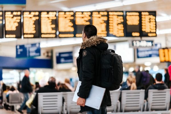 Traveler with backpack in airport terminal rear view