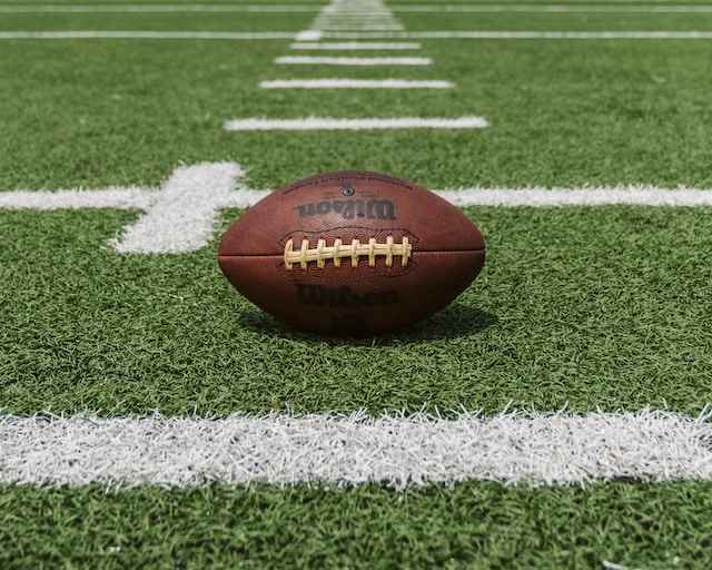 American football on green field with white yard line markings