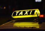 Close-up view of a yellow taxi cab’s rooftop sign illuminated at night, depicting the transportation service provided by taxis in urban areas.